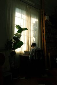 hoogbegaafde volwassene verdiept in gedachten bij raam, kenmerken van hoogbegaafdheid bij volwassenen