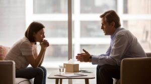 Volwassene in gesprek met begeleider aan tafel, rustige setting