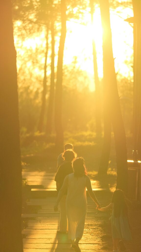 Volwassenen en een kind die samen wandelen in warm zonlicht als metafoor voor relaties als context voor betekenis bij hoogbegaafdheid